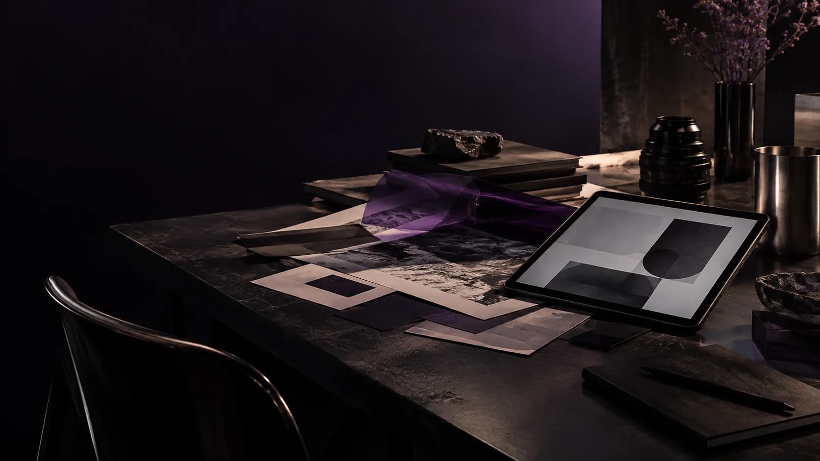 Materiales creativos, una tableta y un lente de cine sobre un set color ciruela profundo